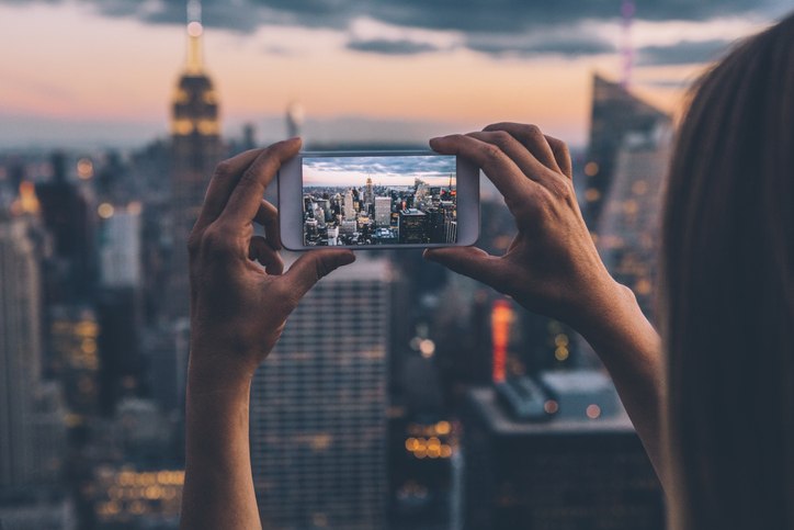 Woman photographing New York skyline at dusk